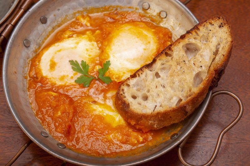 Ovos no Paraiso — ovos fritos em molho de tomate na panela de cobre com pao artesanal
